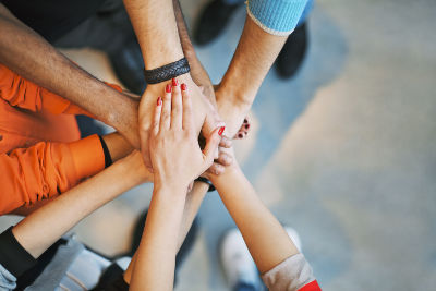 Multiethnic group of young people putting their hands on top of each other. Close up image of young students making a stack of hands. Hands